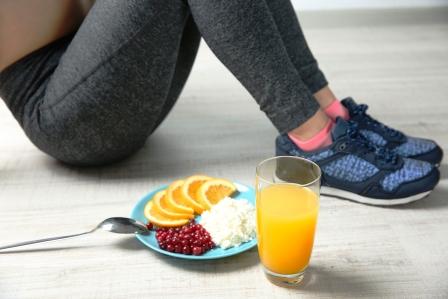 Žena sedí na podlahe a vedľa seba má zdravé raňajky