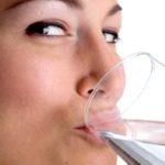 žena pije vodu z pohara